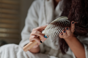 Woman running a white hairbrush through tangled brunette hair